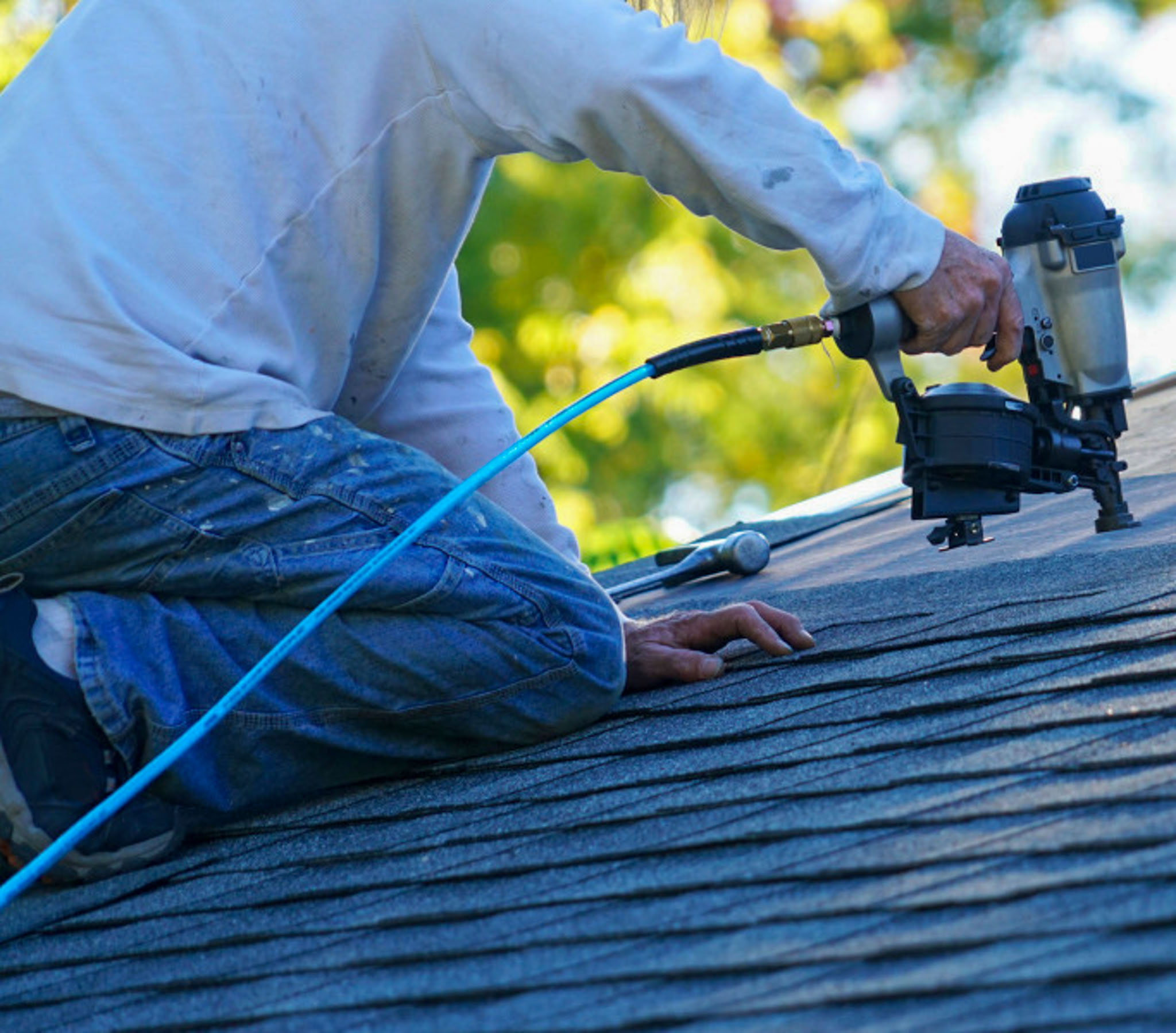 roofer repairing a roof with a nail gun